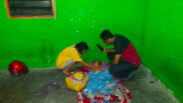 Warga memeriksa korban pembunuhan oleh ayah tiri di tempat kejadian perkara.
