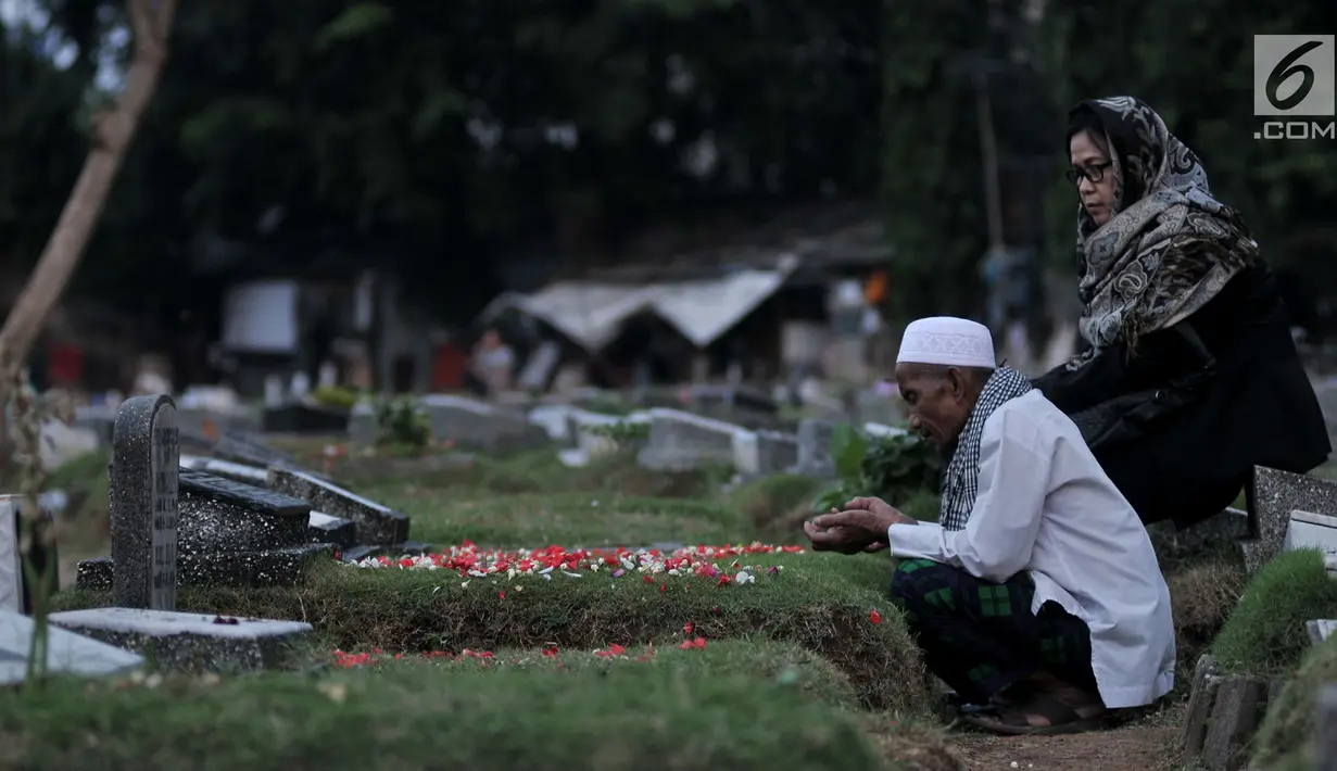 Seorang pria bernama Muhammad Hoir memimpin doa 'Talkin' untuk peziarah di TPU Kemiri, Rawamangun, Jakarta, Selasa (15/5). Pria paruh baya ini telah belasan tahun menggeluti profesi sebagai pembaca doa musiman untuk peziarah. (Merdeka.com/Iqbal S Nugroho)
