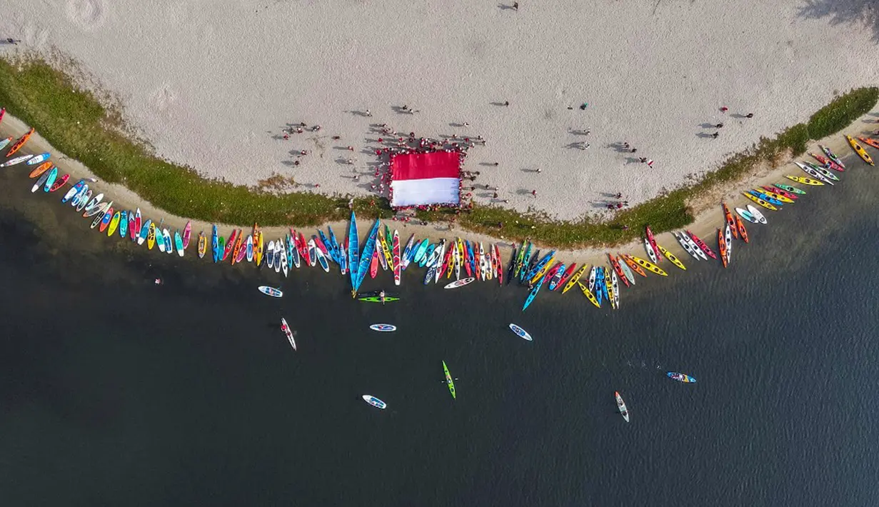 Foto udara memperlihatkan para penggemar kayak sedang mengibarkan bendera Merah Putih sebagai bagian dari perayaan Hari Ulang Tahun (HUT) ke-78 Republik Indonesia (RI) di sebuah pulau kecil di Teluk Jakarta, Jakarta, Kamis (17/8/2023). (BAY ISMOYO/AFP)