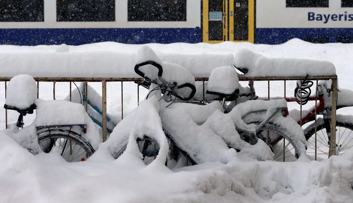 Sejumlah sepeda tertutup salju tebal di Stasiun Kereta Api Schongau, Jerman, Kamis (10/1). Hujan salju lebat diperkirakan akan terus berlanjut. (Karl-Josef Hildenbrand/dpa/AFP)