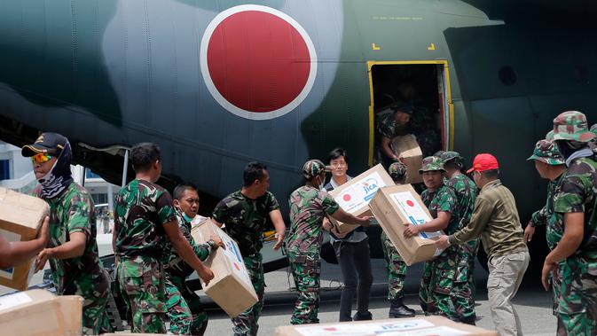 Personil militer Jepang dibantu TNI mengangkut bantuan logistik dari pesawat kargo AU Jepang di bandara Mutiara Sis Al-Jufri, Palu, Sulteng (6/10). Bantuan ini untuk para korban gempa dan tsunami yang menewaskan 1500 jiwa. (AP Photo/Tatan Syuflana)