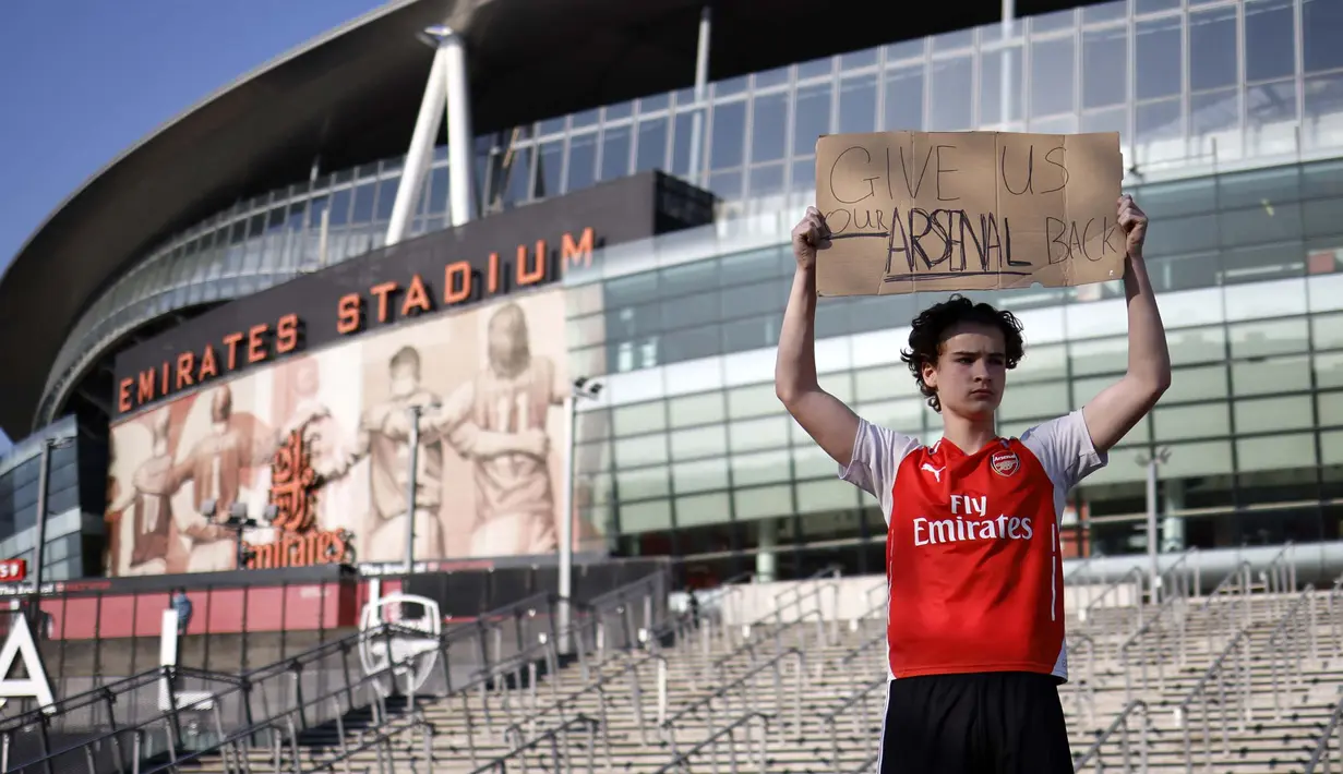 Seorang penggemar Arsenal berdiri dengan memegang spanduk anti Liga Super Eropa di luar Stadion Emirates, London, Senin (19/4/2021). (Foto: AFP/Tolga Akmen)