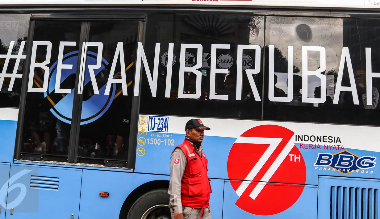 Petugas menjaga perlintasan saat bus TransJakarta koridor 1 dengan stiker tag #Berani Berubah melintas saat Car Free Day (CFD) di Bundaran HI, Jakarta, (14/08). Menjelang HUT Kemerdekaan RI ke 71, sejumlah bus ditempel stiker. (Liputan6.com/Fery Pradolo) 