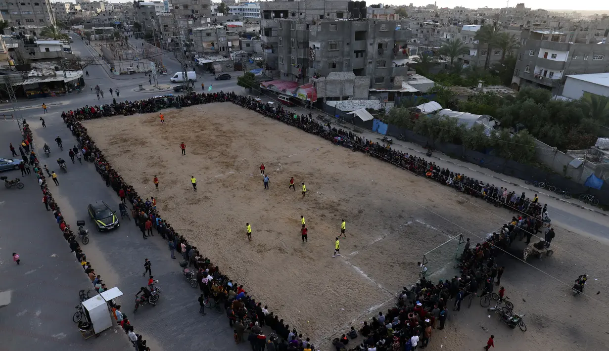 Pemuda Palestina bermain sepak bola di kamp pengungsi sebelum berbuka puasa selama bulan suci Ramadhan di Rafah, di Jalur Gaza selatan (11/4/2022). Sepanjang bulan, umat Islam yang taat harus berpantang dari makanan dan minuman dari fajar hingga matahari terbenam. (AFP/Said Khatib)