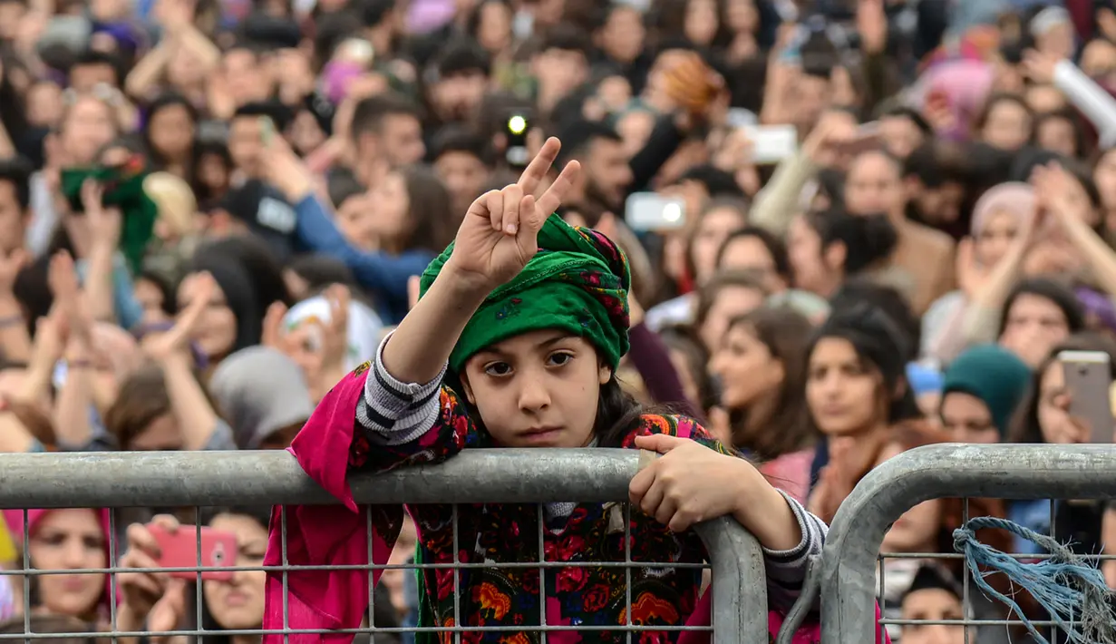 Seorang gadis mengacungkan dua jarinya saat memperingati Women's Day atau Hari Perempuan Internasional di Diyarbakir, Turki, Kamis (8/3). (ILYAS AKENGIN/AFP)