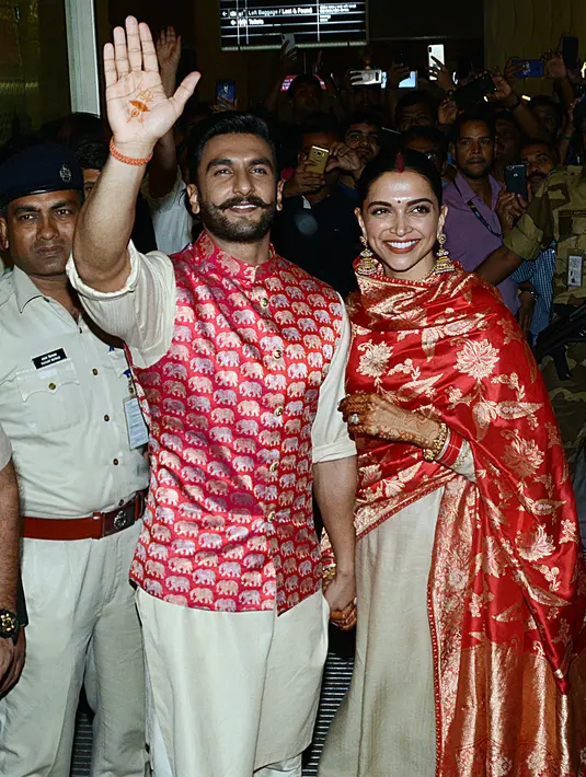 Pasangan bintang Bollywood India, Ranveer Singh dan Deepika Padukone menyapa penggemar yang menyambut mereka di bandara Mumbai, Minggu (18/11). Setelah pacaran selama 5 tahun, Deepika dan Ranveer akhirnya resmi melangsungkan pernikahan di Italia. (AFP)
