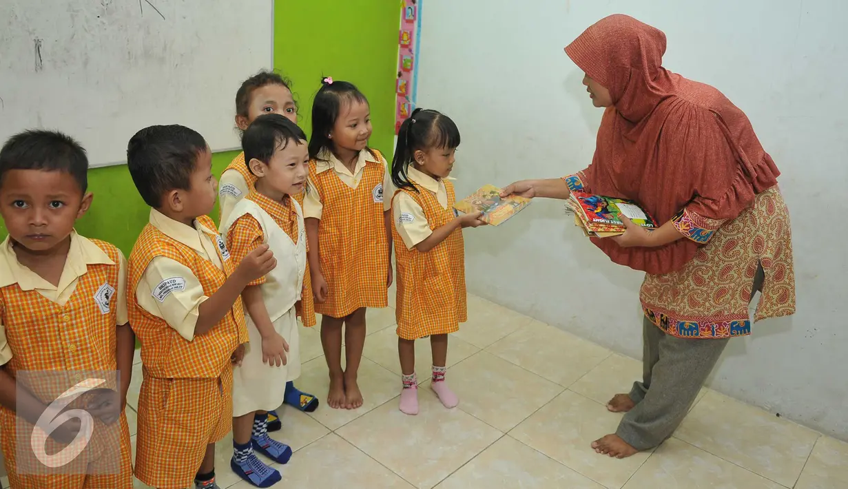 Guru PAUD Seruni Indah memberikan buku kepada murid di kawasan Kalijodo, Jakarta Utara, Selasa (16/2). Rencana penggusuran oleh Pemprov DKI Jakarta membuat khawatir para pengajar dan murid-murid PAUD tersebut. (Liputan6.com/Gempur M Surya)