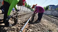 Beberapa pekerja menata ulang batu-batu yang ada di rel kereta api. (14/7/14) (Liputan6.com/Faizal Fanani)