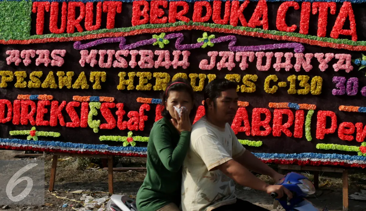Warga melintas di depan Karangan bunga di lokasi jatuhnya pesawat hercules C 130 di jalan jamin ginting, Medan, Kamis (2/7/2015). Karangan bunga sebagai simbol duka cita atas peristiwa yang merenggut ratusan nyawa. (Liputan6.com/Johan Tallo)