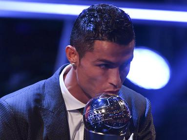 Bintang Real Madrid, Cristiano Ronaldo, mencium trofi pemain terbaik FIFA 2017 di London, Senin (23/10/2017) Ronaldo berhasil mengalahkan Lionel Messi dan Neymar yang juga menjadi nominasi. (AFP/Ben Stansall)