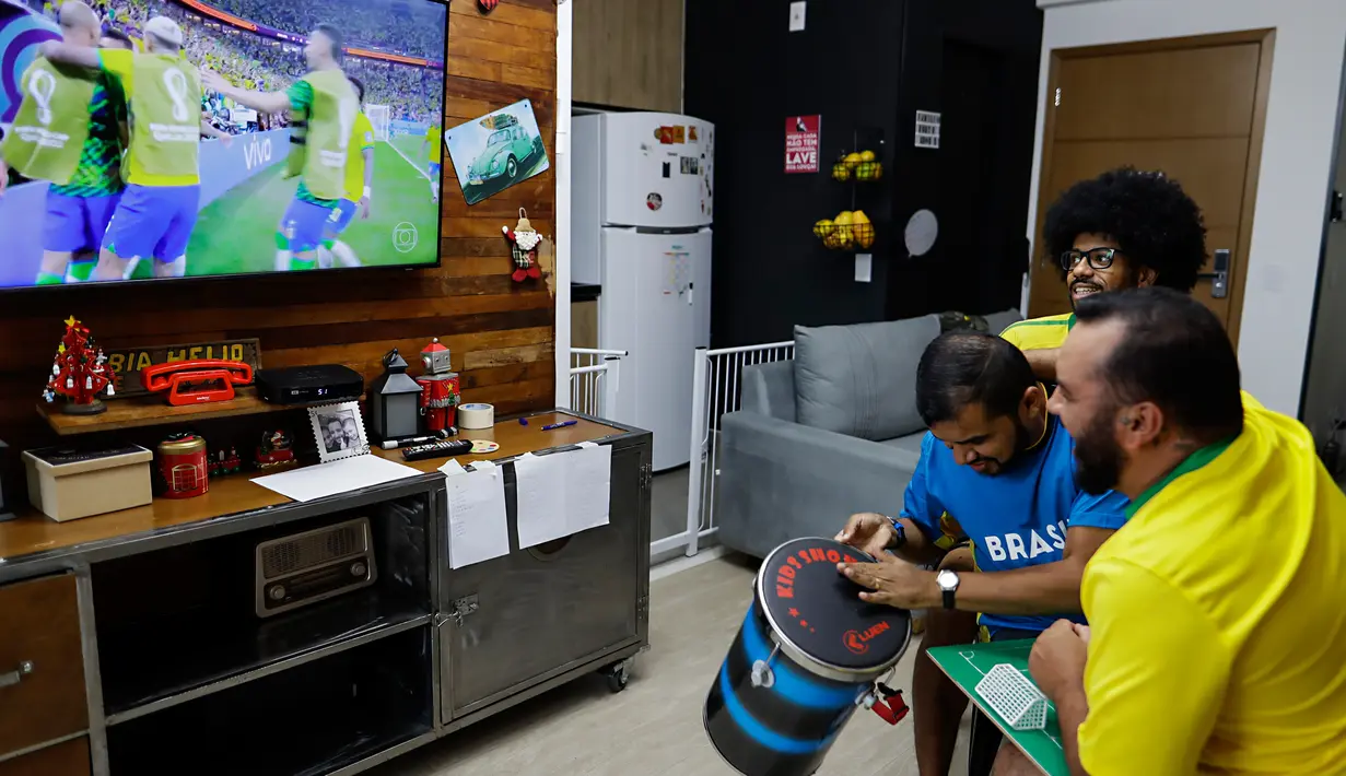 Helio Fonseca (kanan) dan Vinicius Alves (kiri) merayakan gol Brasil dengan teman tuli dan buta mereka Carlos Junior (tengah) saat mereka menonton pertandingan sepak bola Grup G Piala Dunia antara Brasil dan Swiss di Osasco, Sao Paulo, Brasil, 28 November 2022. Fonseca dan Alves menggunakan meja taktil dan sentuhan pada tubuh tunanetra dan tunarungu untuk menunjukkan kepada mereka pergerakan bola dan para pemain selama pertandingan sepak bola. (AP Photo/Marcelo Chello)