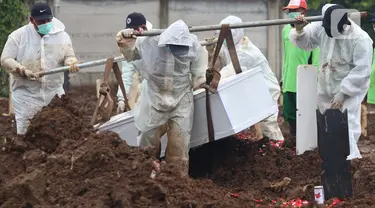 Petugas membawa peti berisi jenazah dengan protokol COVID-19 di TPU Srengseng Sawah, Jakarta, Kamis (21/1/2021). Sebagian lahan TPU Srengseng Sawah yang dijadikan lokasi pemakaman jenazah Covid-19 sejak Selasa (12/1) lalu, kini hanya tersisa 79 petak makam. (Liputan6.com/Helmi Fithriansyah)