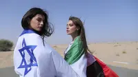 Model Israel May Tager (kiri) memegang bendera Israel dan model Dubai asal Rusia Anastasia Bandarenka memegang bendera Uni Emirat Arab saat pemotretan di Dubai, Uni Emirat Arab, 8 September 2020. Israel dan UEA menekankan manfaat ekonomi yang dapat dihasilkan normalisasi. (AP Photo/Kamran Jebreili)