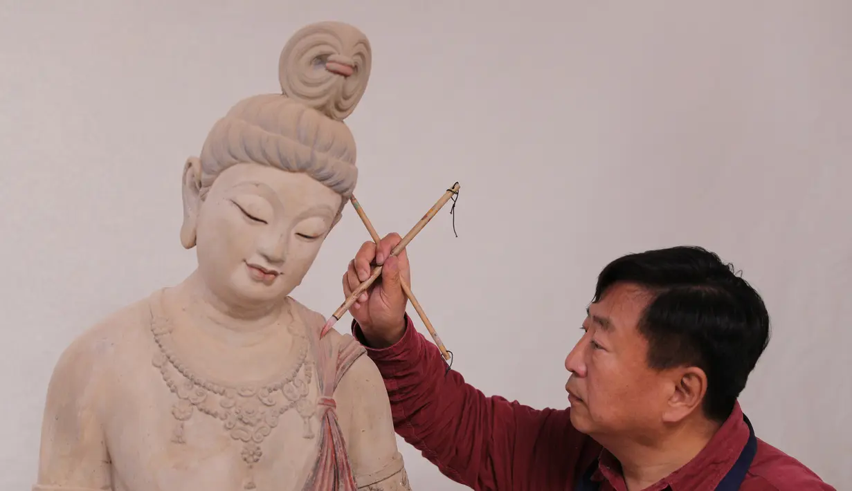 Seniman Du Yongwei mewarnai sebuah patung dengan cat di Dunhuang, Provinsi Gansu, China, Minggu (5/4/2020). Seni patung warna-warni merupakan bentuk kesenian tradisional di Dunhuang. (Xinhua/Du Zheyu)