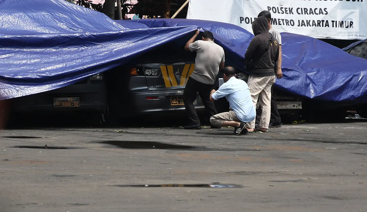 Petugas melihat melihat kondisi mobil yang dirusak di Polsek Ciracas, Jakarta, Rabu (12/12). Mobil yang dirusak di antaranya mobil polisi dan mobil Puspom Kodam. (Liputan6.com/Herman Zakharia)