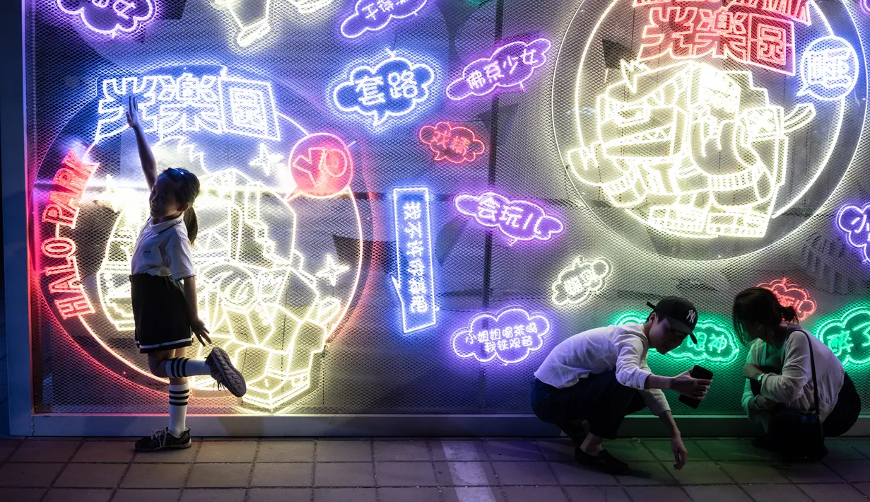 Sejumlah pengunjung berfoto dengan latar belakang seni instalasi cahaya yang berjudul "Halo Park" di Chaoyang Park, Beijing (7/5). Pameran ini merupakan karya dari tim seni dan multimedia kreatif internasional. (AFP/Fred Dufour)