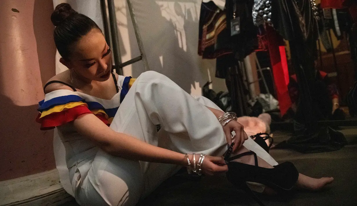 Seorang model menyesuaikan sepatu high heelsnya di belakang panggung sebelum memamerkan koleksi oleh Zhang Kejia selama China Fashion Week di Beijing (26/3). (AFP Photo/Nicolas Asfouri)