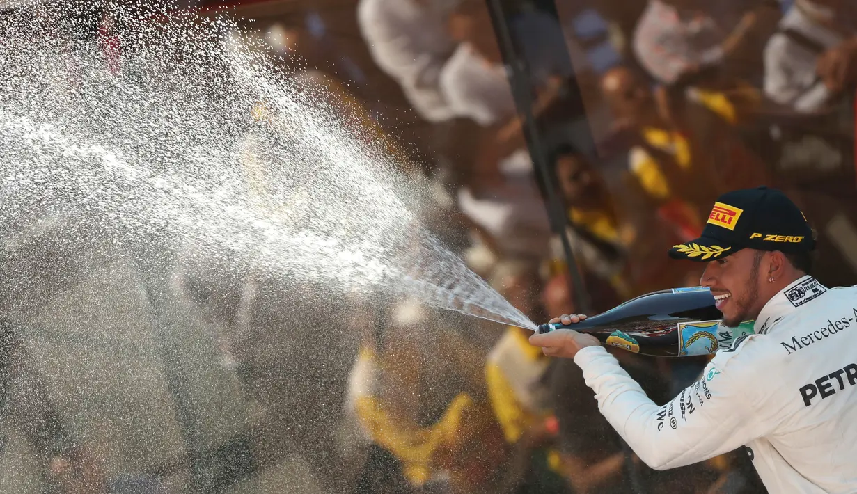 Pembalap Mercedes, Lewis Hamilton membuka sampanye setelah memenangi balapan F1 GP Spanyol di Sirkuit Catalunya, Minggu (14/5). Sepanjang balapan, ia mendapat tekanan sengit dari Sebastian Vettel yang finis di urutan kedua. (AP Photo/Emilio Morenatti)