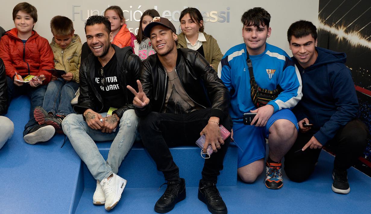 Pemain Barcelona, Dani Alves (ketiga kiri) dan Neymar (ketiga kanan) berpose dengan sejumlah anak saat melakukan kunjungan amal di Rumah Sakit Vall d' Hebron, Barcelona, Senin (4/1/2016). (AFP PHOTO / Josep LAGO)