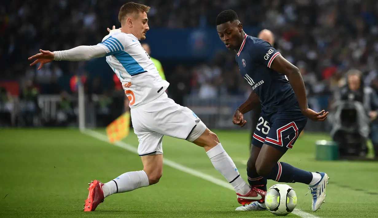 Gelandang Olympique MarseilleValentin Rongier (kiri) berebut bola dengan bek Paris Saint-Germain (PSG) Nuno Mendes pada laga Liga Prancis pekan ke-32 di Parc des Princes, Senin (18/4/2022) dini hari WIB. PSG vs Marseille berakhir dengan skor 2-1. (FRANCK FIFE / AFP)