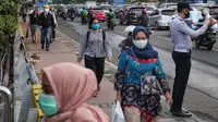 Sejumlah orang berjalan di trotoar pada saat jam pulang kantor di Kawasan Sudirman, Jakarta, Senin (8/6/2020). Aktivitas perkantoran dimulai kembali pada pekan kedua penerapan Pembatasan Sosial Berskala Besar (PSBB) transisi pandemi COVID-19. (Liputan6.com/Johan Tallo)