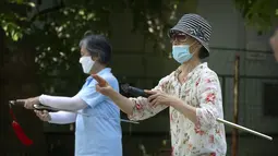 Perempuan yang mengenakan masker melakukan rutinitas olahraga di taman umum di Beijing, Jumat (8/7/2022). Ibu kota China, Beijing, tampaknya telah membatalkan rencana untuk mengeluarkan mandat yang mengharuskan orang menunjukkan bukti vaksinasi COVID-19 untuk masuk ke ruang publik tertentu setelah penolakan di kalangan penduduk. (AP Photo/Mark Schiefelbein)