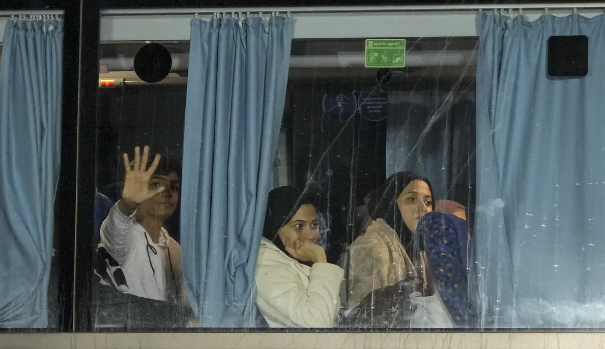 Orang-orang yang dievakuasi dari Gaza duduk di dalam bus setelah tiba dengan pesawat dari Mesir di pangkalan angkatan udara Baza 90 di Otopeni, Rumania, Rabu, 8 November 2023. (AP Photo/Andreea Alexandru)