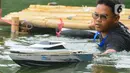 Seorang mahasiswa mendorong kapal cepat tak berawak ke tengah danau saat mengikuti Kontes Kapal Cepat Tak Berawak Nasional (KKCTBNdi Danau Kenanga, Kampus UI, Depok, Jawa Barat, Selasa (24/10/2023). (merdeka.com/Arie Basuki)