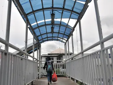 Pejalan kaki melintasi JPO yang tidak terawat di JPO Imigrasi Jakarta Timur, Kamis (17/1). JPO yang berada di depan Kantor Imigrasi Jakarta Timur dalam kondisi tidak terawat, seperti atap yang sudah rusak dan penuh coretan. (Merdeka.com/Iqbal S. Nugroho)