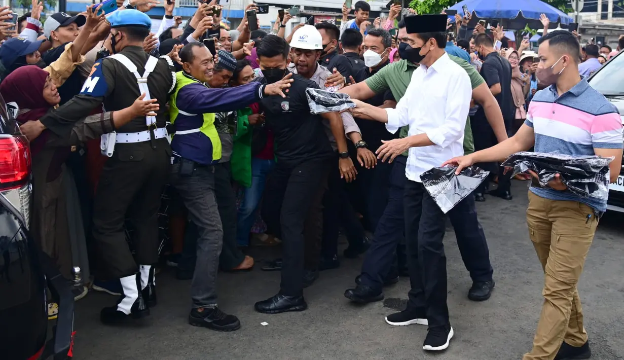 Presiden Joko Widodo  membagi-bagikan kaos pada warga yang sudah menunggu di depan Masjid Raya Sheikh Zayed Solo, Minggu (20/11/2022). Dalam kunjungan tersebut, Jokowi bersama ibu negara Iriana Jokowi dan cucunya Jan Ethes. (Foto: Muchlis Jr - Biro Pers Sekretariat Presiden)