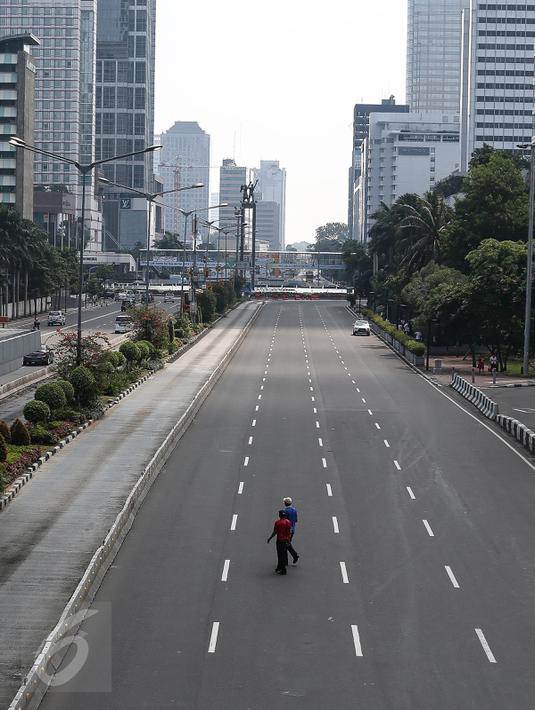 Warga menyeberang melintasi jalan protokol yag lengang di kawasan MH Thamrin, Jakarta, Selasa (6/7). Hampir semua jalan di Ibu Kota lengang saat sebagian besar warga mudik untuk merayakan Lebaran di kampung halaman. (Liputan6.com/Faizal Fanani)