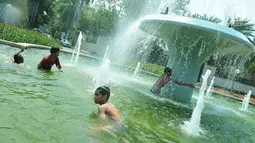 Sejumlah anak mandi di bundaran air mancur Jalan Teuku Umar, Jakarta Pusat, Sabtu (23/9). Cuaca panas ibu kota memaksa anak-anak menceburkan diri di kolam untuk menyejukkan badan. (Liputan6.com/Helmi Afandi)