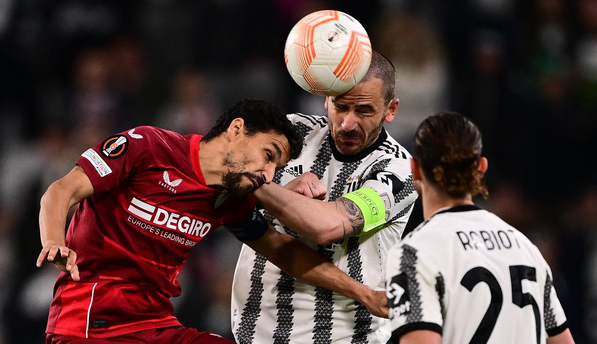 Pemain Juventus, Leonardo Bonucci (tengah) berebut bola dengan pemain Sevilla, Jesus Navas pada laga leg pertama semifinal Liga Europa 2022/2023 di Allianz Stadium, Juventus, Jumat (12/05/2023) WIB. Laga berakhir dengan skor 1-1. (AFP/Marco Bertorello)