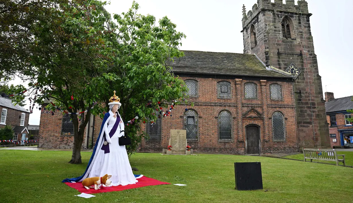 <p>Ratu Elizabeth II dari Inggris yang dirajut seukuran manusia terlihat di halaman Gereja St Luke di Kapel Holmes, barat laut Inggris, pada 30 Mei 2022. Sebuah kelompok masyarakat lokal, The Holmes Chapel Community Yarn Bombers telah memenuhi desa dengan barang-barang rajutan patriotik untuk merayakan Platinum Jubilee Ratu. (Paulus ELLIS / AFP)</p>