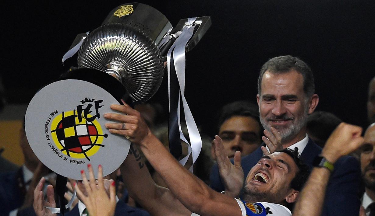 Kapten Valencia, Daniel Parejo, mengangkat trofi Copa del Rey usai mengalahkan Barcelona pada laga Copa del Rey di Stadion Benito Villamarin, Sevilla, Sabtu (25/5). Barcelona kalah 1-2 dari Valencia. (AFP/Pau Barrena)