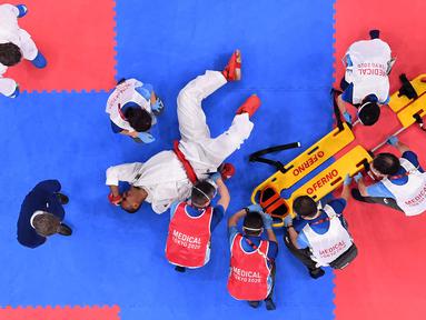 Atlet Jerman Jonathan Horne mendapat perawatan dari petugas medis setelah cedera saat melawan Gogita Arkania dari Georgia dalam pertandingan karate pada Olimpiade Tokyo 2020 di Nippon Budokan, Tokyo, Sabtu (7/8/2021). (Foto: AFP/Alexander Nemenov)