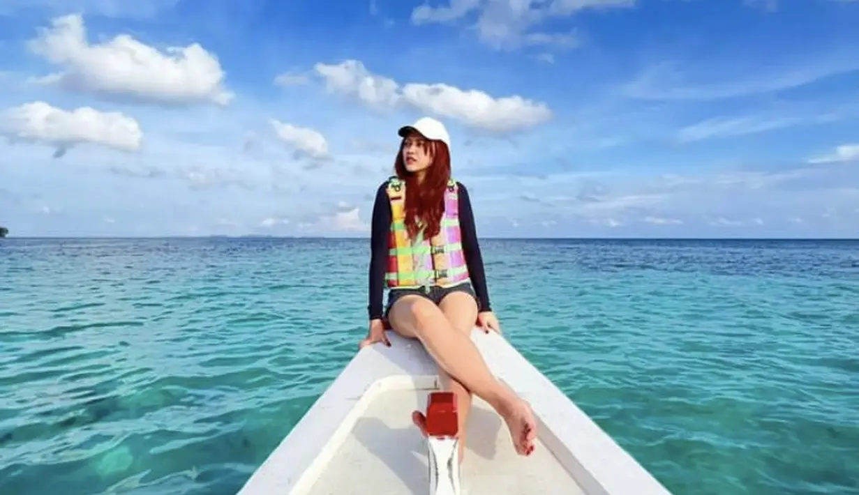 Berada di tengah laut, ia tampil dengan atasan lengan panjang hitam diatas  life jacketnya. Tampak ia mengenakan short pants dan topi putihnya. (@happy_asmara77)