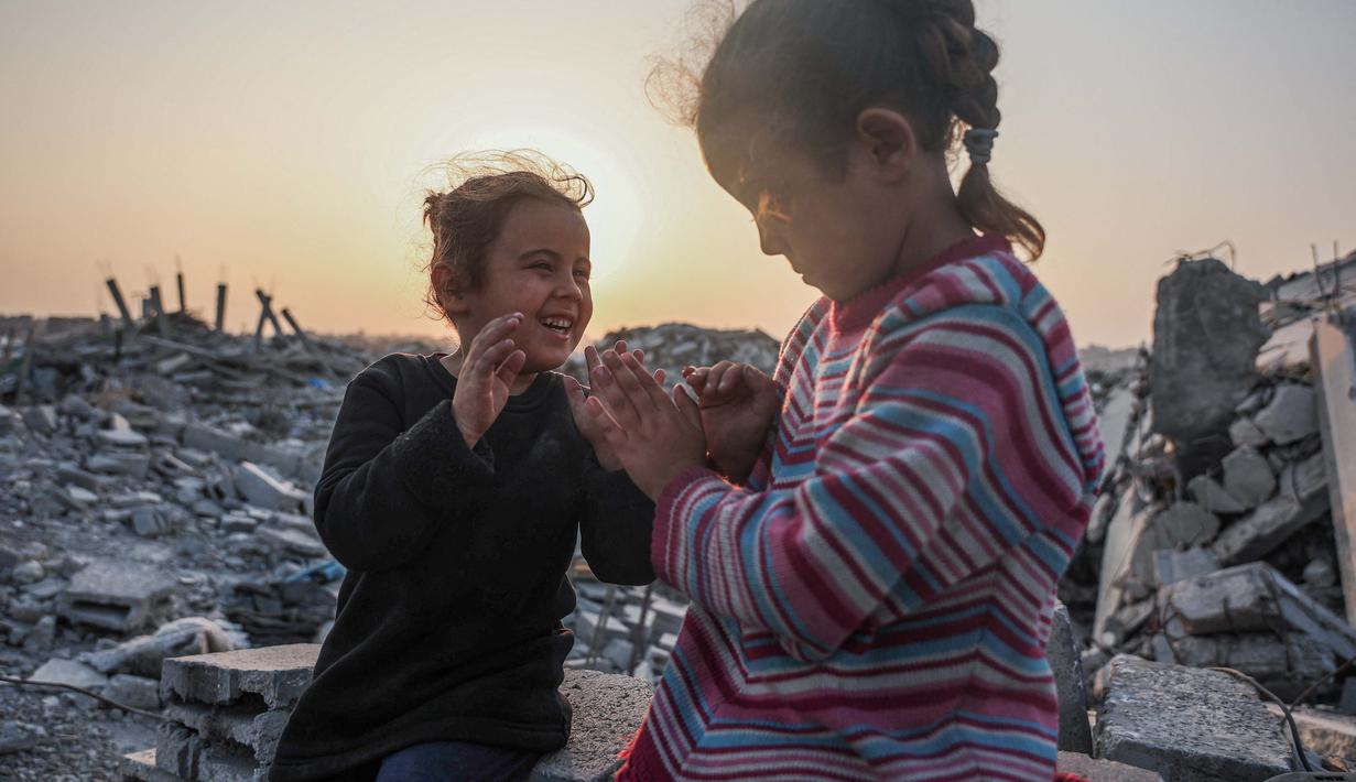 Laporan Kantor Koordinasi Urusan Kemanusiaan (OCHA) yang disampaikan Juru Bicara PBB Farhan Haq mengatakan pada Selasa (4/11/2025) bahwa pihaknya bersama para mitra kemanusiaan terus memperluas operasi mereka untuk menjangkau lebih banyak warga terdampak. Tampak dalam foto, gadis-gadis Palestina bermain di antara puing-puing bangunan yang hancur di Jabalia, di bagian utara Jalur Gaza, pada Jumat 7 November 2025. (Omar AL-QATTAA/AFP)