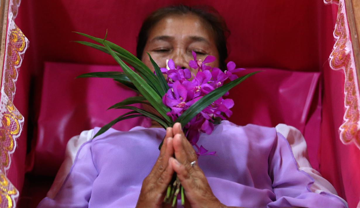 Seorang pemuja berdoa saat berbaring dalam peti mati di kuil Takien, pinggiran kota Bangkok, Thailand, Senin (31/12). Mereka mempercayai ritual ini dapat membantu menyingkirkan nasib buruk dan dianggap sebagai awal dari kehidupan baru. (AP/Sakchai lalit)