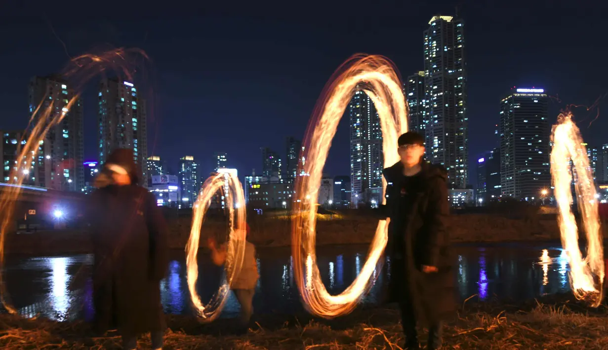 Peserta membuat lingkaran api jelang perayaan "Jeongwol Daeboreum" (Bulan Purnama) di Seoul, Korea Selatan (1/3). Permainan ini dipercaya dapat menyuburkan tanah dan menyingkirkannya hama sehingga memastikan hasil panen melimpah. (AFP Photo/Jung Yeon-je)