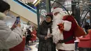Seorang perempuan berpose untuk foto kenang-kenangan bersama Sinterklas di sebuah pusat perbelanjaan di Shanghai pada 17 Desember 2023. (AP Photo/Wayne Zhang)
