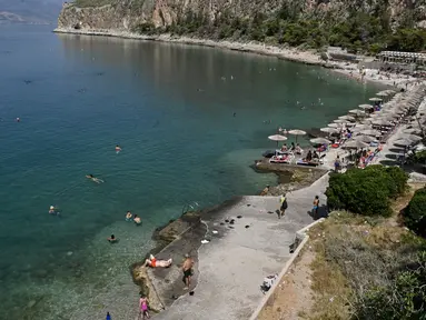 Penduduk setempat dan turis mendinginkan diri di sebuah pantai di kota wisata Nafplion, sekitar 200 km barat daya Athena selama cuaca panas di Yunani, pada 14 Juli 2023. (AFP/Louisa Gouliamaki)