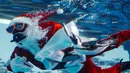 Penyelam berkostum Sinterklas juga terlihat membawa karangan bunga Natal dan memberi makan ikan. Tampak dalam foto, seorang penyelam berkostum Sinterklas memberi makan seekor penguin di Akuarium Sunshine dalam persiapan untuk acara spesial Natal mendatang di Tokyo pada 1 Desember 2025. (Foto oleh Kazuhiro NOGI / AFP)