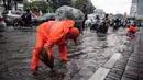 Petugas dari Dinas Kebersihan membuang genangan air kedalam selokan usai hujan deras dikawasan Tugu Tani, Jakarta, Kamis (12/10). Tingginya curah hujan membuat genangan disisi jalan. (Liputan6.com/Faizal Fanani)