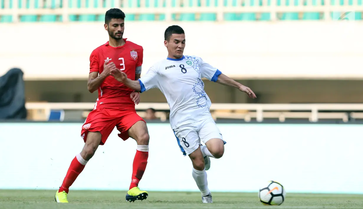 Pemain belakang Bahrain, Ahmed Bughammar (kiri) berusaha menahan laju pemain Uzbekistan, Kenjabaev Islom saat laga PSSI Anniversary Cup 2018 di Stadion Pakansari, Kab Bogor, Senin (30/4). Laga berakhir imbang 3-3. (Liputan6.com/Helmi Fithriansyah)