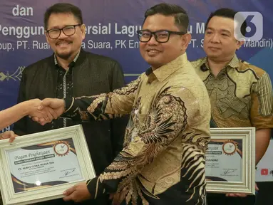 Head of Protocol & Corporate Affairs Surya Citra Media (SCM), Irnawati W Kahardja (kiri) menerima apresiasi kepada pengguna komerisal dari Lembaga Manajemen Kolektif Nasional (LMKN) di kawasan Kuningan, Jakarta, Kamis (19/12/2024). (Liputan6.com/Herman Zakharia)