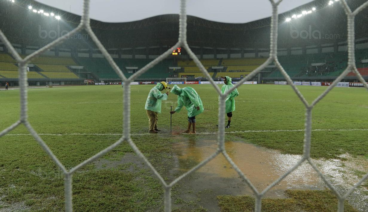 Petugas membuat lubang resapan untuk menguras air yang menggenangi lapangan di Stadion Patriot, Bekasi, Senin (13/11/2017). Drainase yang buruk menyebabkan lapangan terendam air. (Bola.com/M Iqbal Ichsan)
