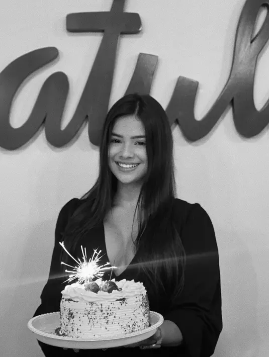 Raiane Lima saat merayakan ulang tahunnya yang ke-21. Ia tersenyum manis sembari memegang kue ulang tahun. Raiane juga terlihat seksi dengan busana model kerah v-neck. (Instagram/raianelima8)