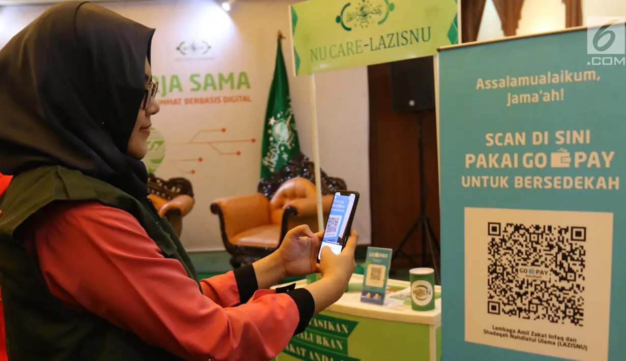 Model mencoba QR Code melalui dompet digital Go-Pay saat peluncuran kerja sama strategis pemberdayaan ekonomi umat berbasis digital di Jakarta (16/7/2019). Gojek, Go-Pay, dan NU Care-LazisNU menjalin kerja sama untuk pembayaran zakat, infaq, dan sedekah secara nontunai. (Liputan6.com/Angga Yuniar)