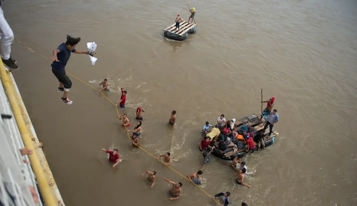 Imigran Honduras yang sedang menuju Amerika Serikat melompat dari jembatan perbatasan untuk menyeberang ke Meksiko di Tecun Uman, Guatemala, 19 Oktober 2018. Imigran berharap mereka mendapat pekerjaan di AS. (AP Photo/Oliver de Ros)